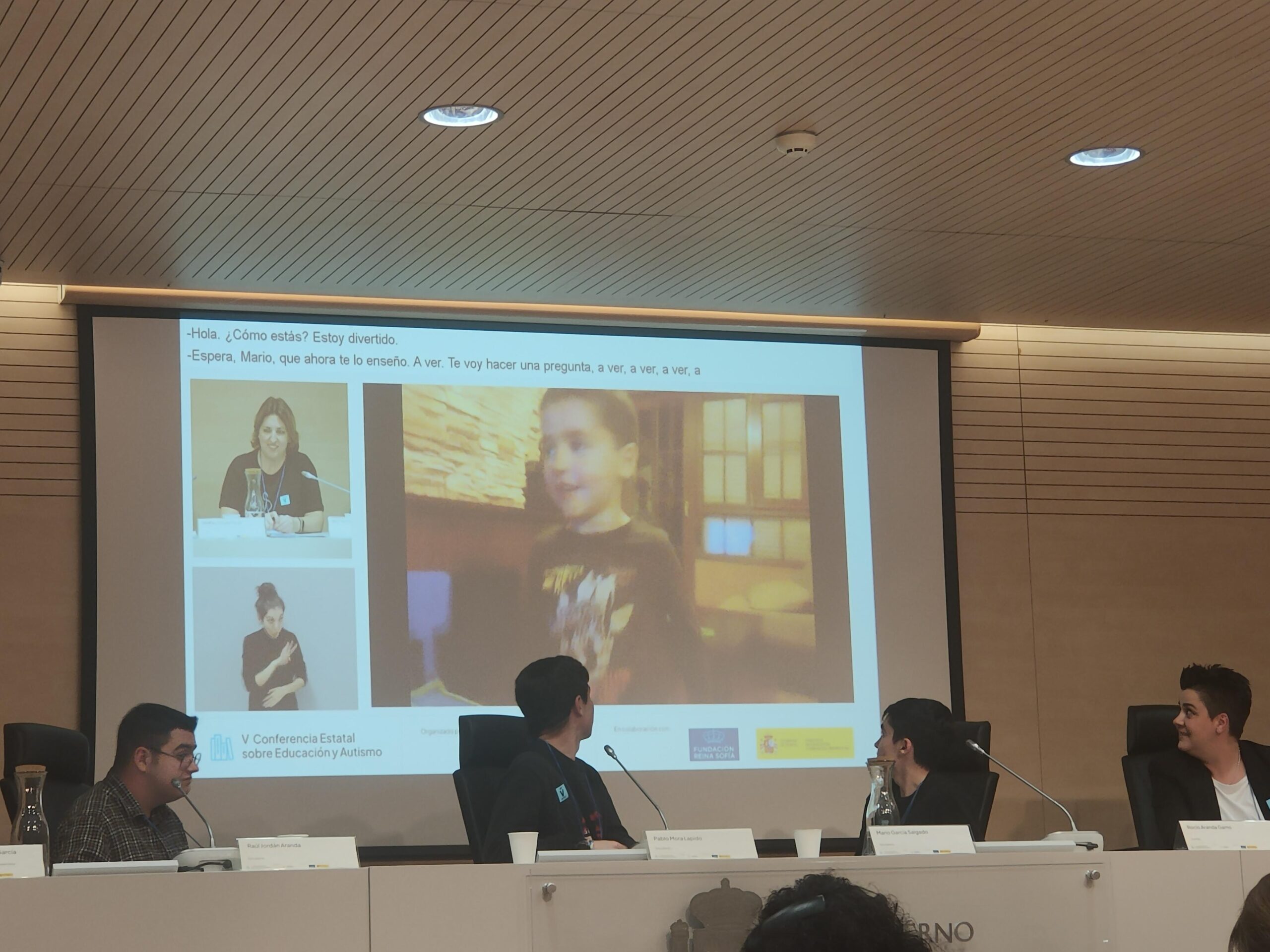 Foto de la ponencia donde se ve una diapositiva con un vídeo de uno de los chicos de pequeño